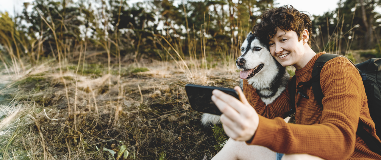 Young person takes a selfie of himself and his dog while hiking