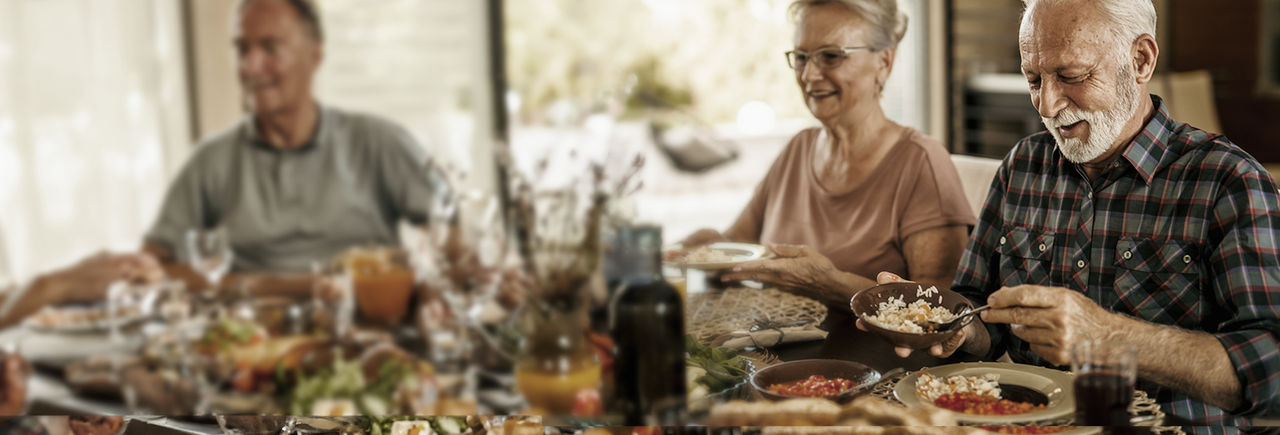 Three older people are happy to enjoy a meal together