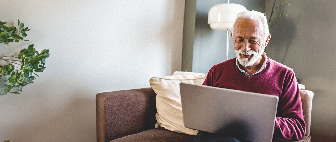 Friendly, smiling, older man searches for DBS clinic on his laptop